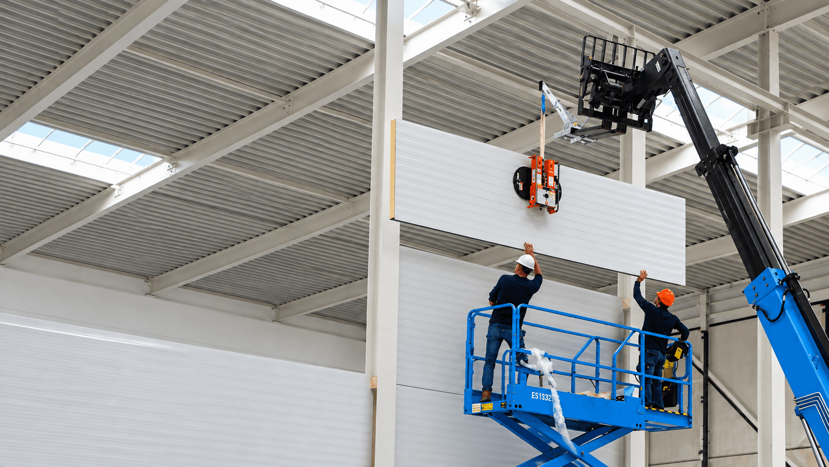 Trabajadores instalando panel sandwich con ventosa VIAVAC desde elevador en nave industrial